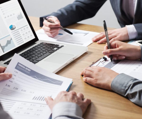 Business professionals working together at office desk, hands close up pointing out financial data on a report, teamwork concept